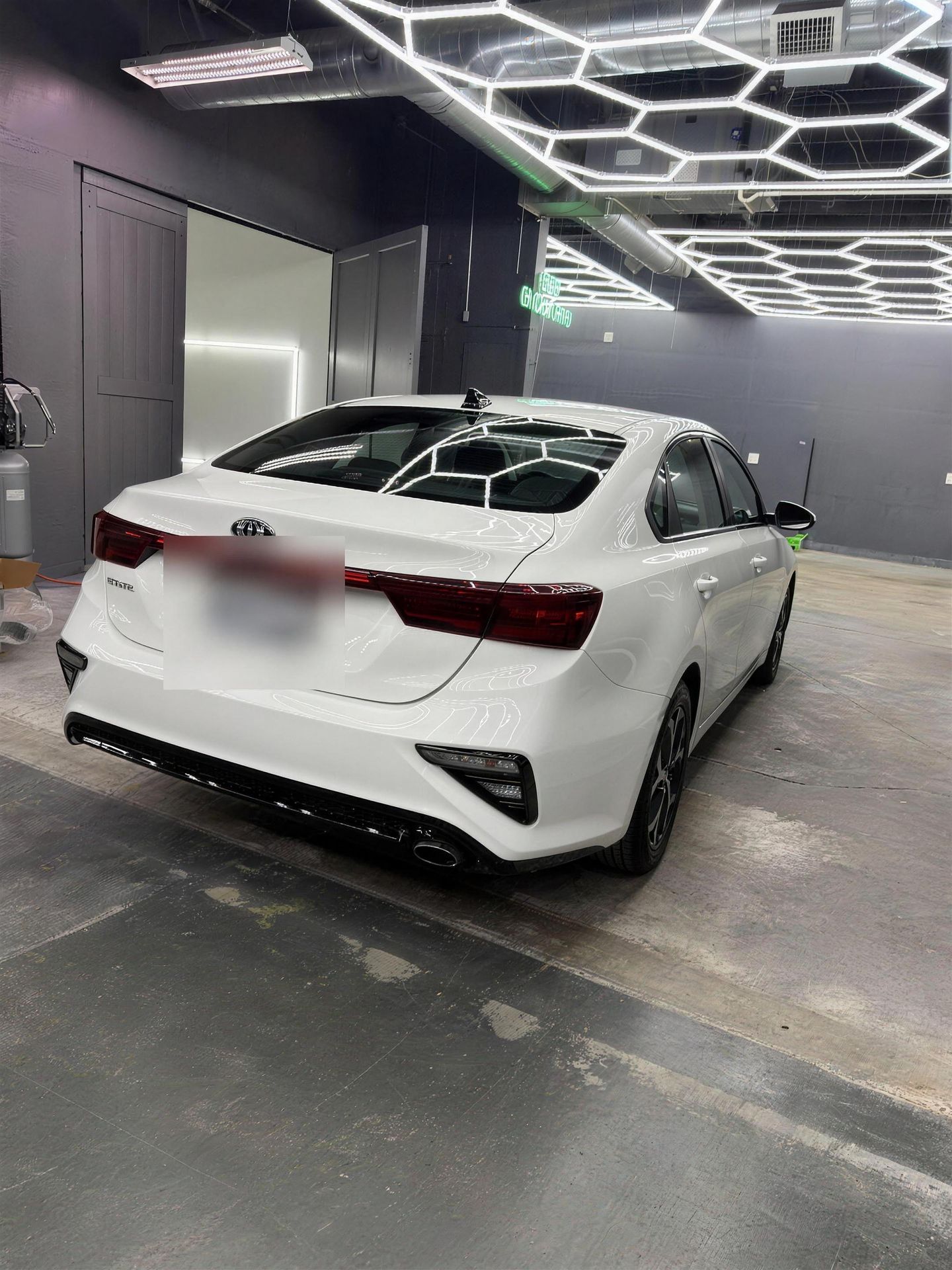 Repaired white Kia Forte under the shop lights